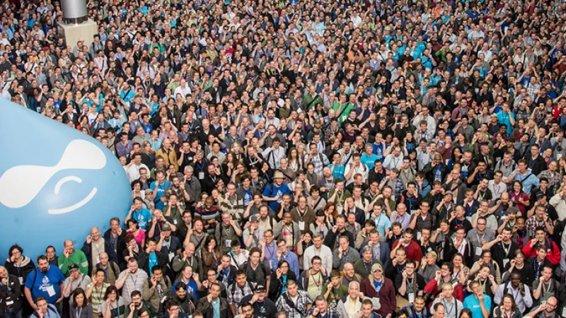 Large crowd gathered outdoors with a blue Drupal logo balloon.