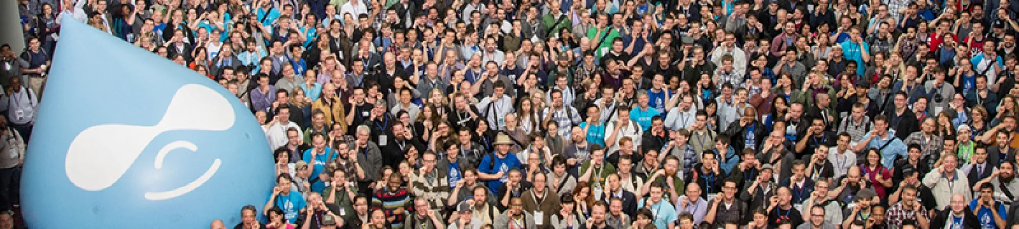 Large crowd gathered outdoors with a blue Drupal logo balloon.